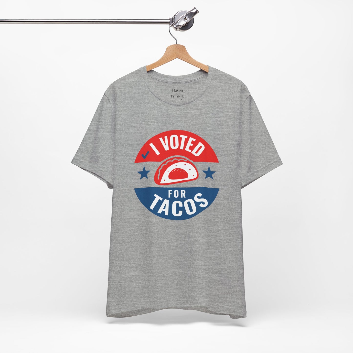 Gray t-shirt with 'I Voted for Tacos' graphic on a hanger against a white background