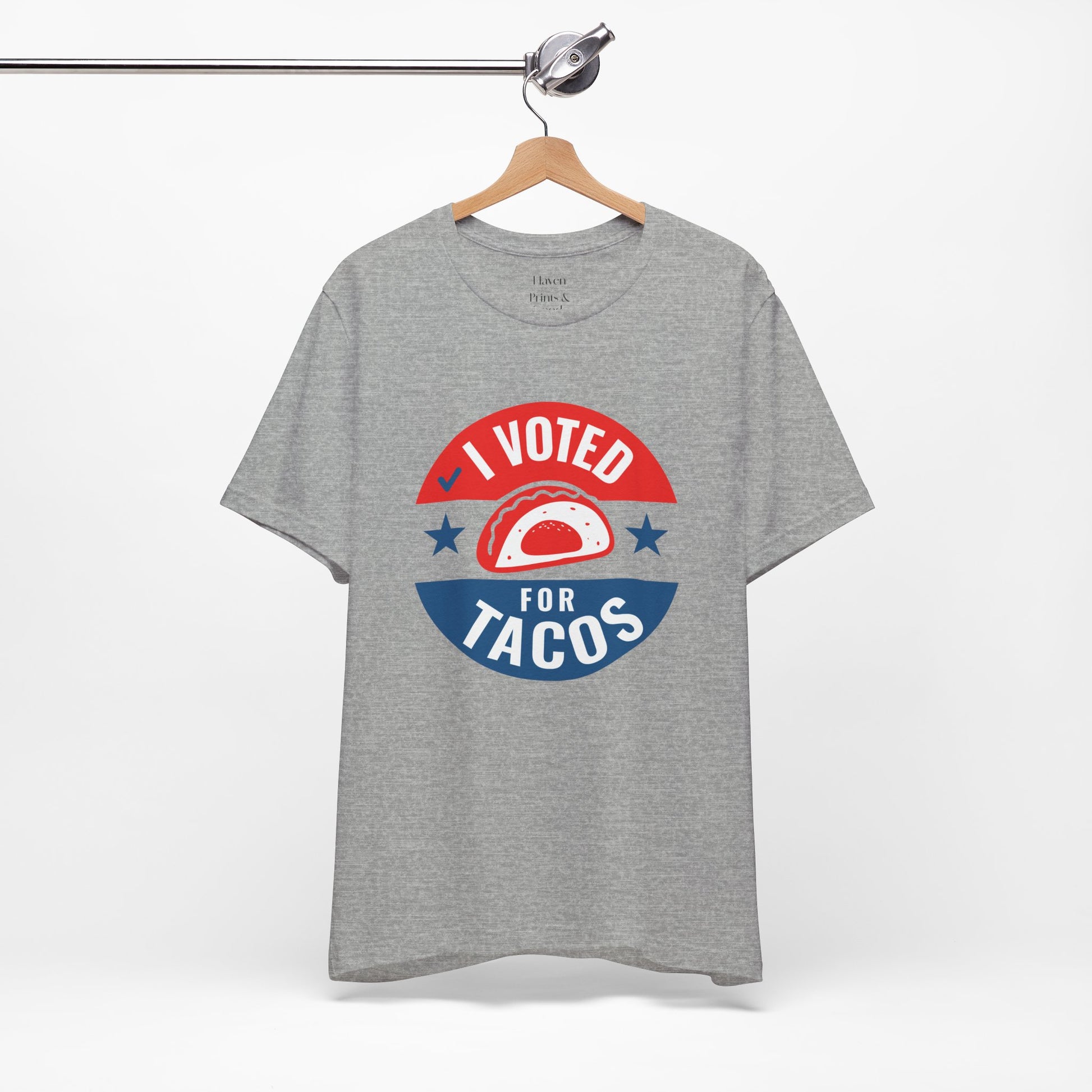 Gray t-shirt with 'I Voted for Tacos' graphic on a hanger against a white background